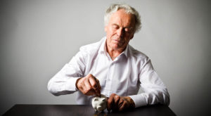 tfsa for retirement. older man putting money into piggy bank