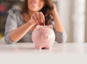 A woman is seen placing a coin into a piggy bank