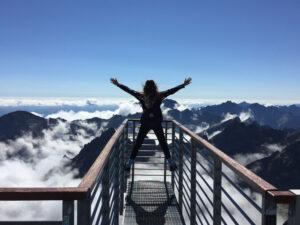 woman at the top of a mountain cheering, as an allegory to defeating debt