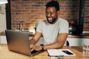 smiling man using laptop computer in his home