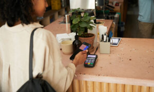 A woman is buying a coffee at an artisanal café, using her KOHO credit card.