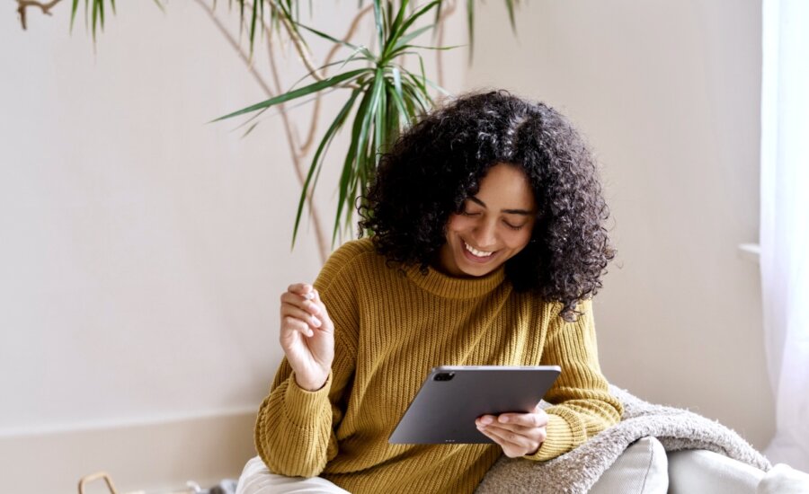 Woman smiles at her tablet in her living room