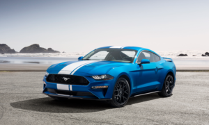 A blue-and-white Ford Mustang on a beach