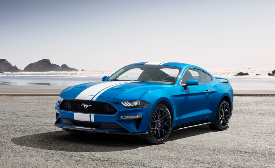 A blue-and-white Ford Mustang on a beach