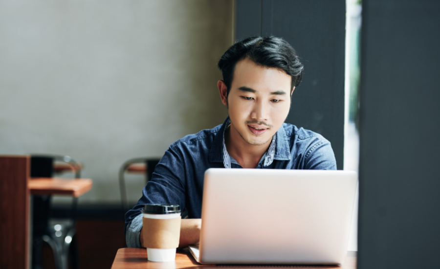 A young man uses his laptop in a cafe