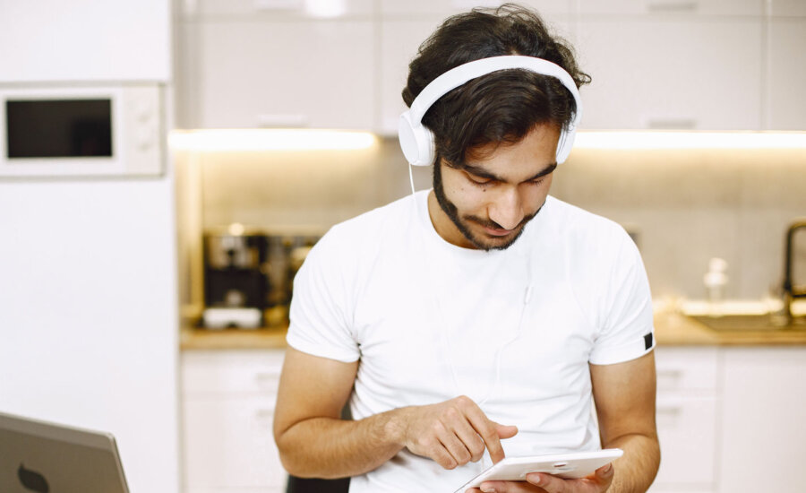 A Canadian man wearing headphones for self-care when dealing with financial stress.