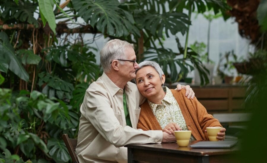 A retired couple sit with a cup of coffee