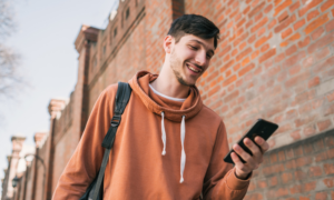 A smiling man checks his investments on his phone