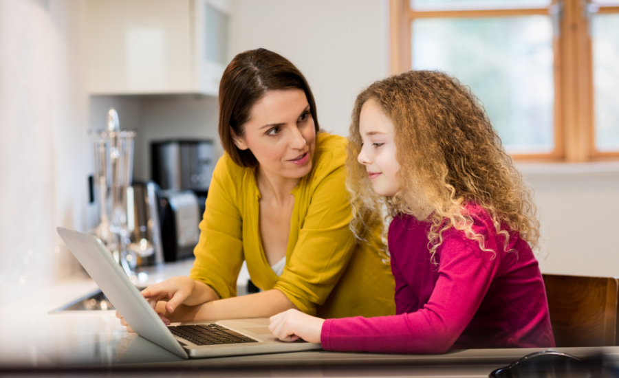 A mom and daughter look at a laptop