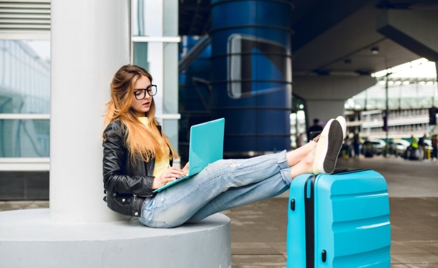 A young woman works on her laptop from the airport