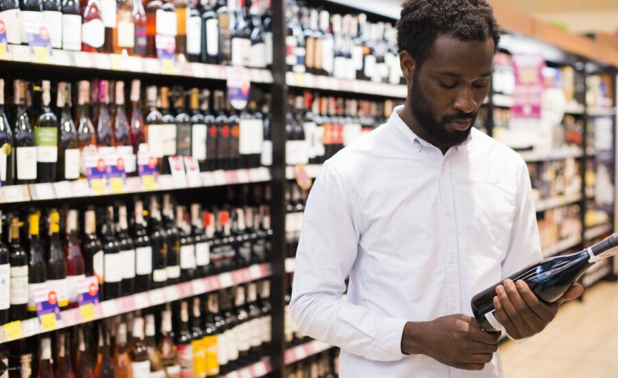 customer inspects wine bottle in liquor store