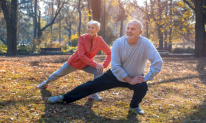 An older couple does stretches in a park