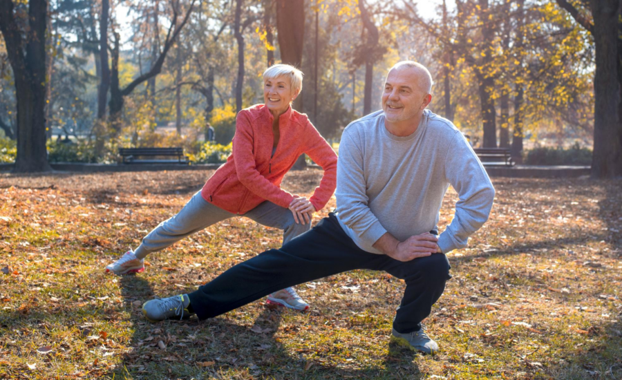 An older couple does stretches in a park