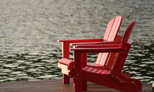 Two empty Muskoka chairs on a deck, to inspire the contrast of the perks of a cottage in Canada and the financial implications.