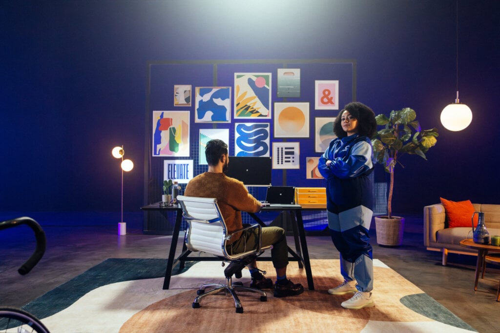 Two people in front of a wall of framed art