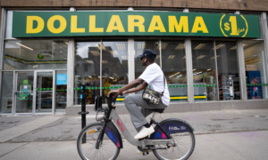 Man riding a bike past a Dollarama store