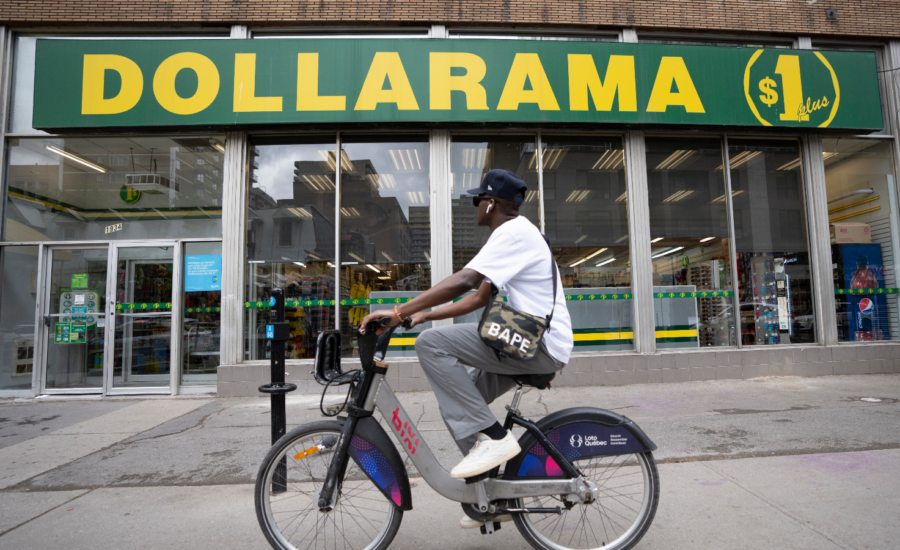 Man riding a bike past a Dollarama store