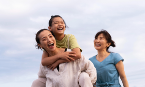 A grandmother, daughter and granddaughter walk on a beach