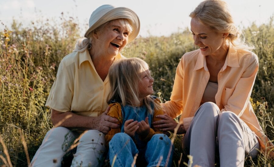 A woman with her daughter and grand-daughter outside in the fall