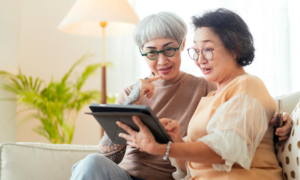 Two middle-aged women check interest rates on a tablet