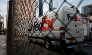 FedEx truck behind a fence, as its price drops in response to earnings.