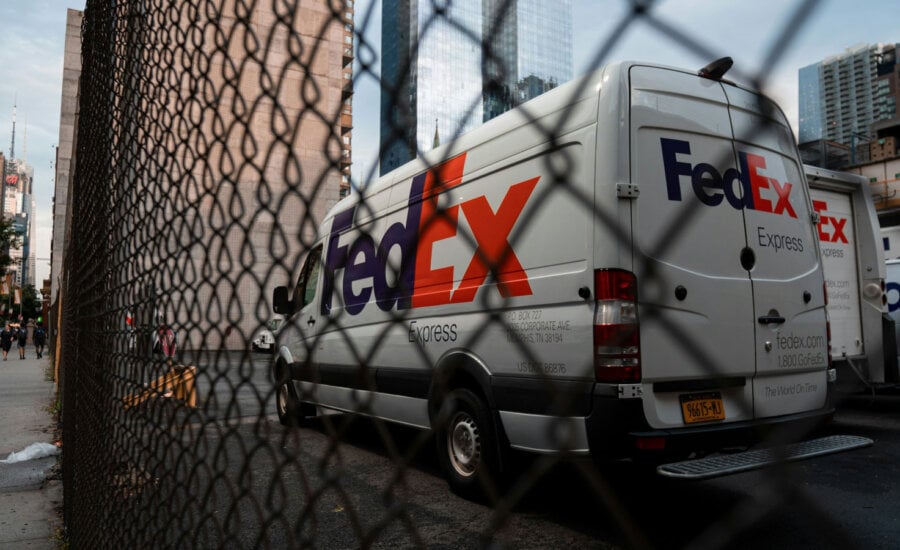 FedEx truck behind a fence, as its price drops in response to earnings.