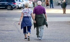 A Canadian retired couple walking together on a street, thinking about decumulation.