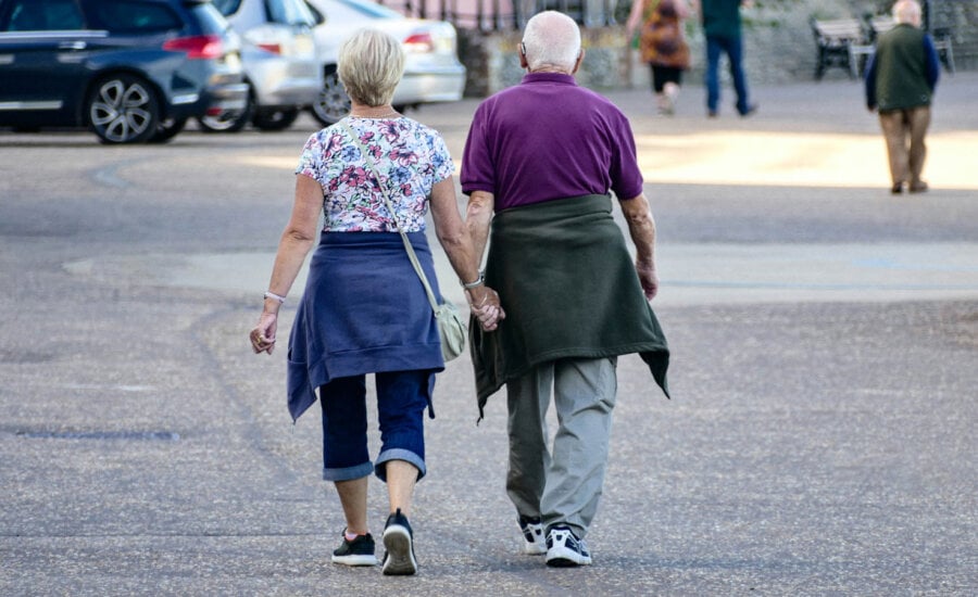 A Canadian retired couple walking together on a street, thinking about decumulation.