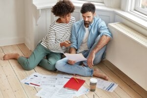 couple examines mortgage renewal documents on living room floor