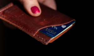 A hand holds a credit card in a leather cardholder