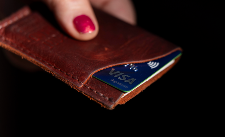 A hand holds a credit card in a leather cardholder