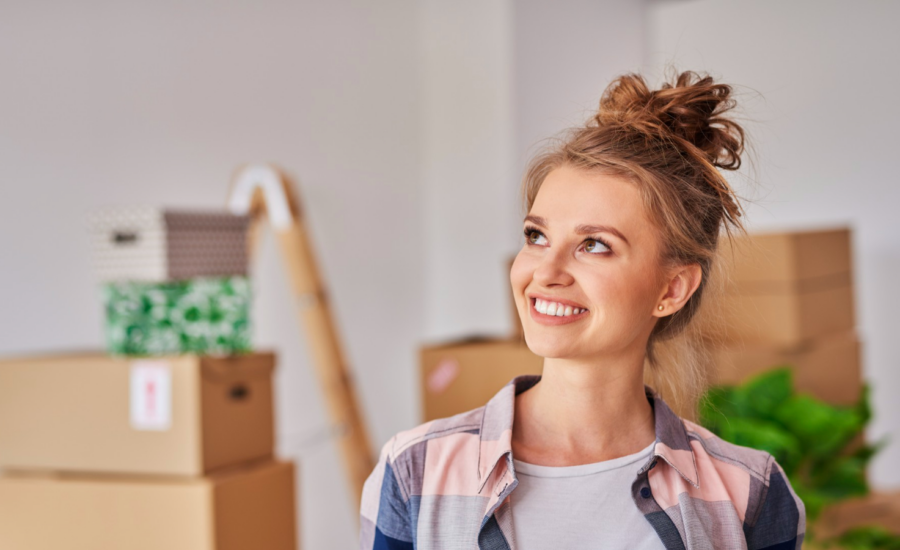 A young woman surrounded by moving boxes in her new home