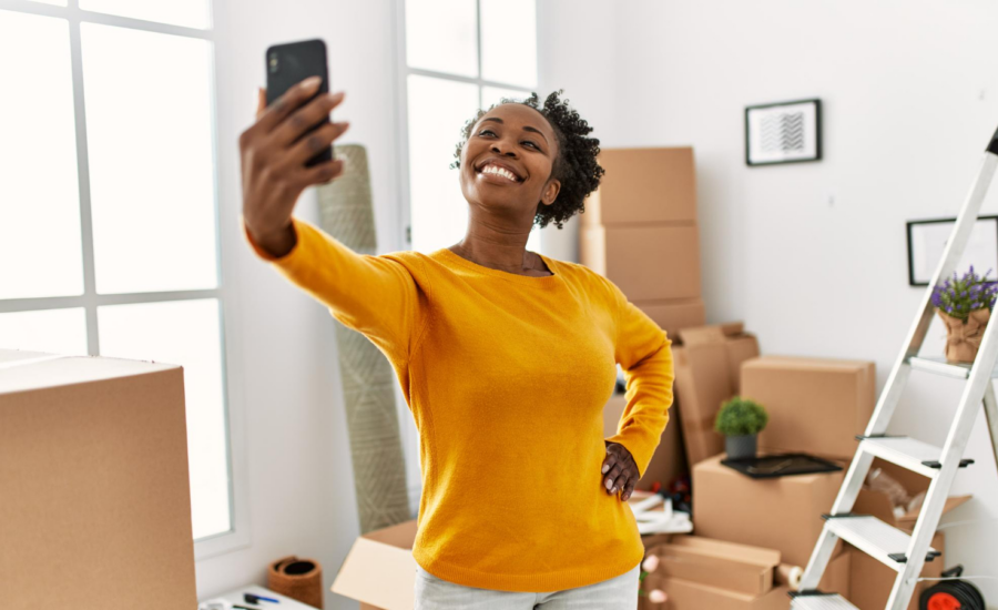 A smiling young woman takes a selfie in her new home.