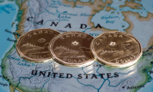 Three loonies sit on a map on the Canadian-U.S. border