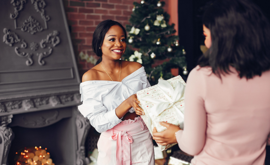 A woman gives another woman a wrapped holiday gift