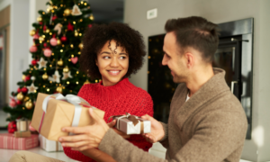 A young man and woman exchange holiday gifts