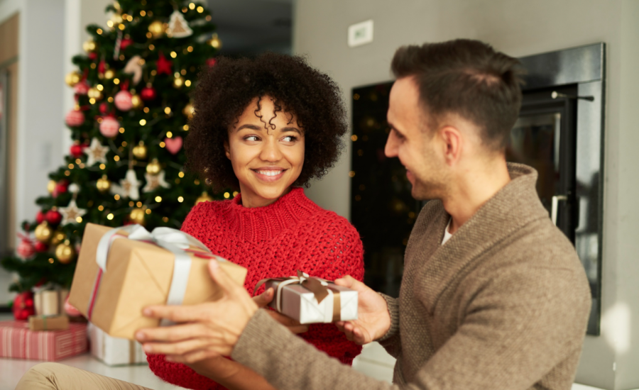 A young man and woman exchange holiday gifts