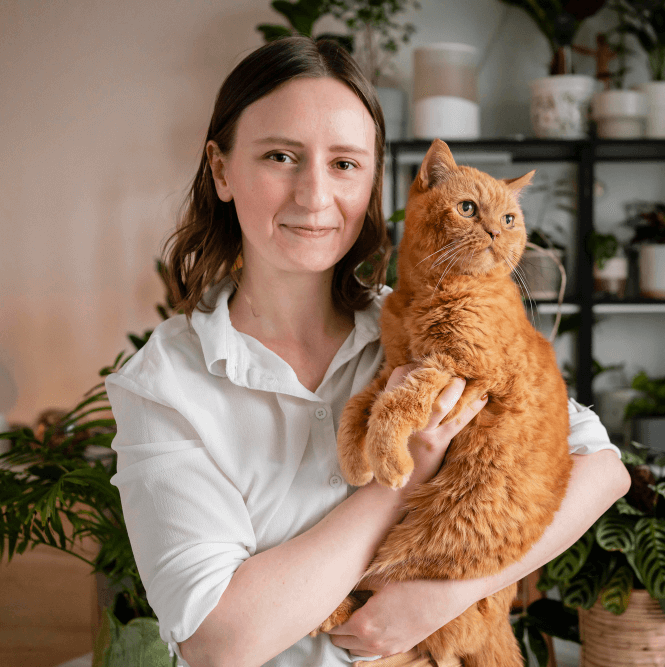 A young woman holds an orange cat