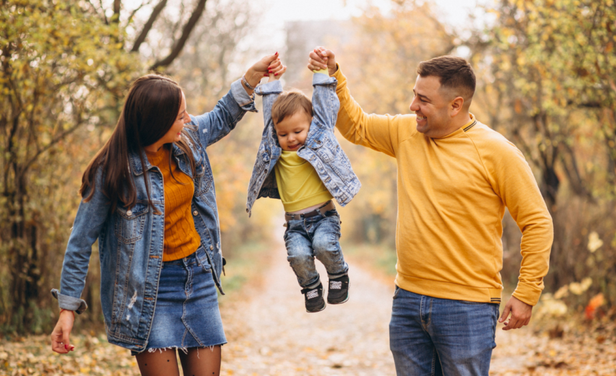 A young couple walks with their toddler son.