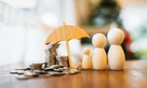 Wooden figurines of a family and an umbrella sheltering stacks of coins