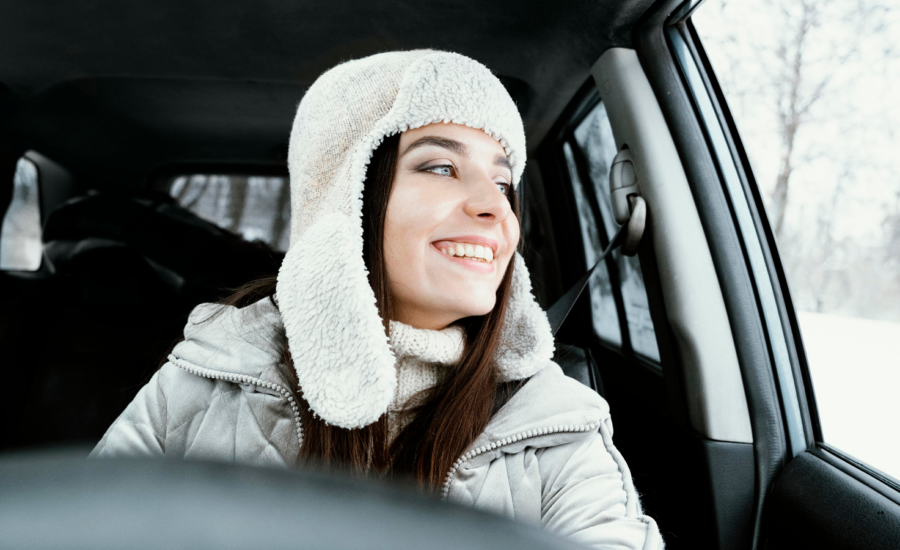 A smiling woman drives a car in winter