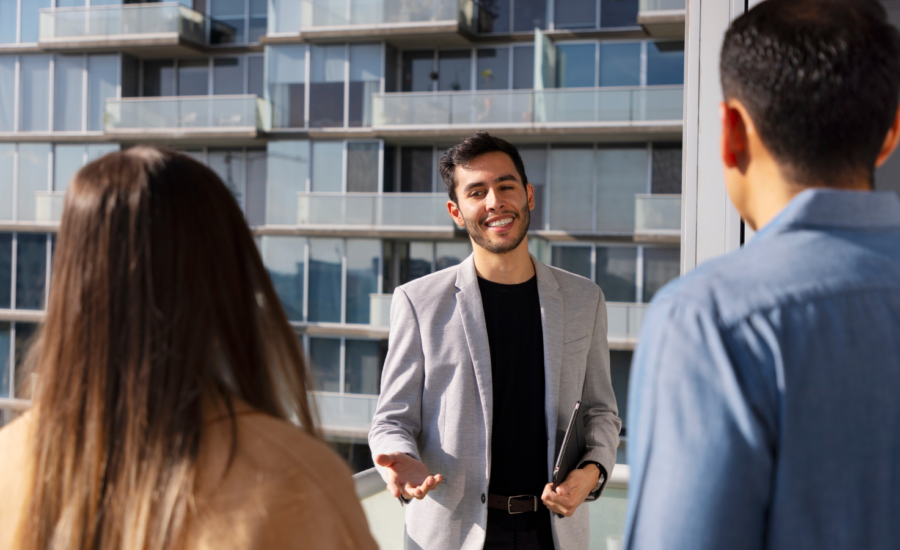 A landlord meets with two potential tenants outside a condo building