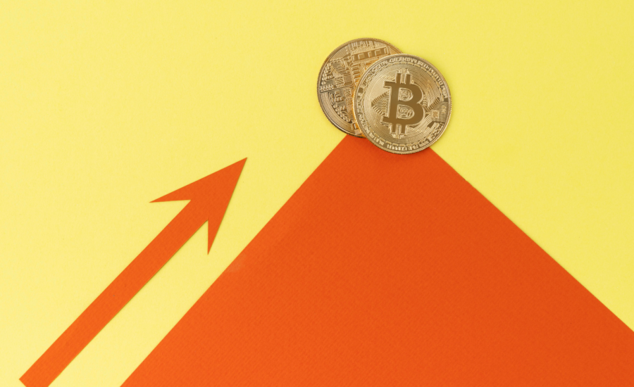 Two gold bitcoins sit on top of a peak, poised to roll down