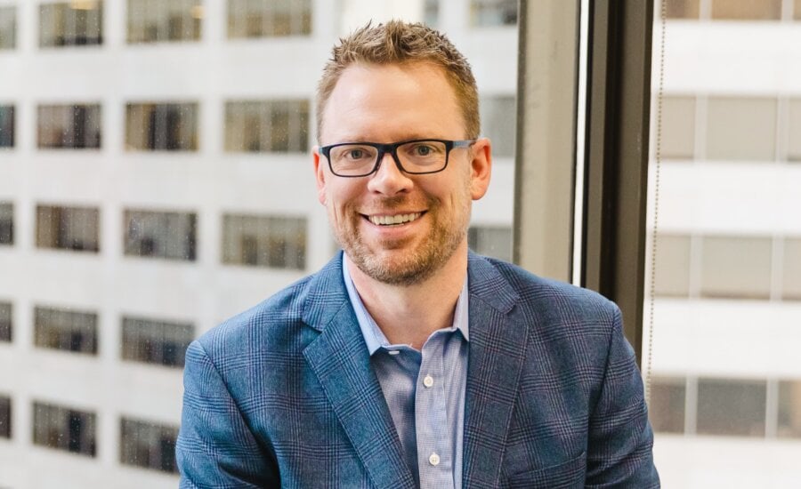 Waist up photo of financial advisor Sean Wilson with a city building in the background.