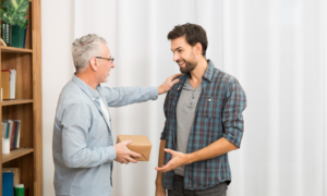 A senior-age man gives a box to his son