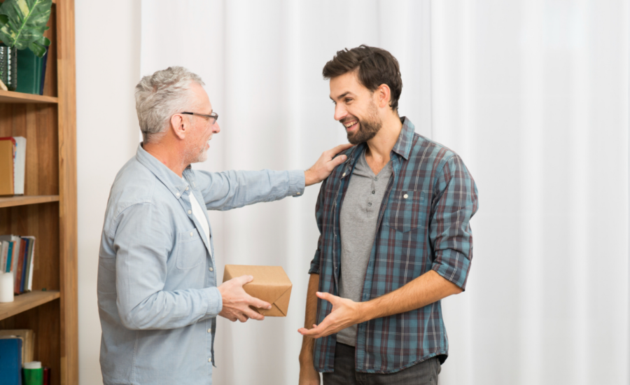 A senior-age man gives a box to his son