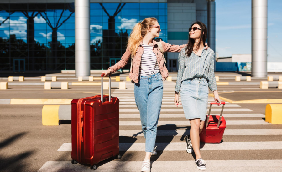 Two women leaving an airport with their suitcases