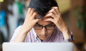 A man looks worried as he uses his computer