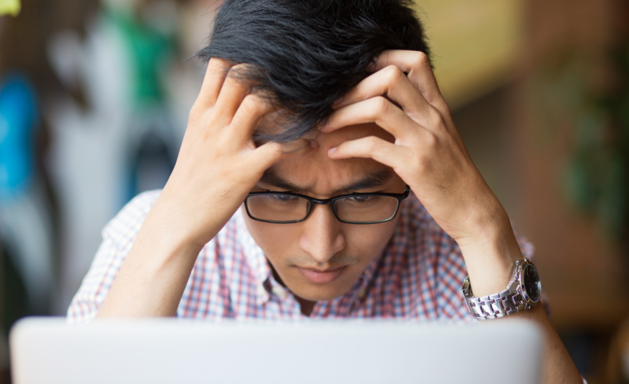 A man looks worried as he uses his computer