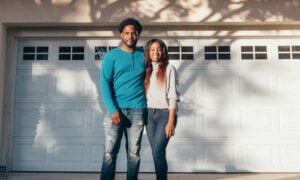 Canadian couple outside their home, wondering about the cost of their mortgage payments and if they will rise.